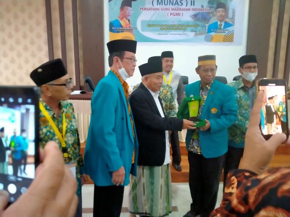 Prof Dr KH Asep Saifuddin Chalim, MA, mendapat cindramata dari Ketua Panitia Munas II PGMI, Dr Kaswad Sartono, disaksikan Ketua Umum PGMI Syamsudin di Ruang Bir Ali Asrama Haji Makassar, Sabtu (4/12/2021). Foto: M Mas