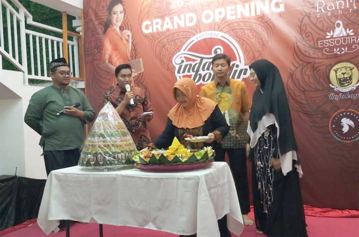 Pemilik Indah Bordir, Laila Cahyawati (kerudung orange) memotong tumpeng pada opening Indah Bordir di jalan MERR Rungkut Surabaya.