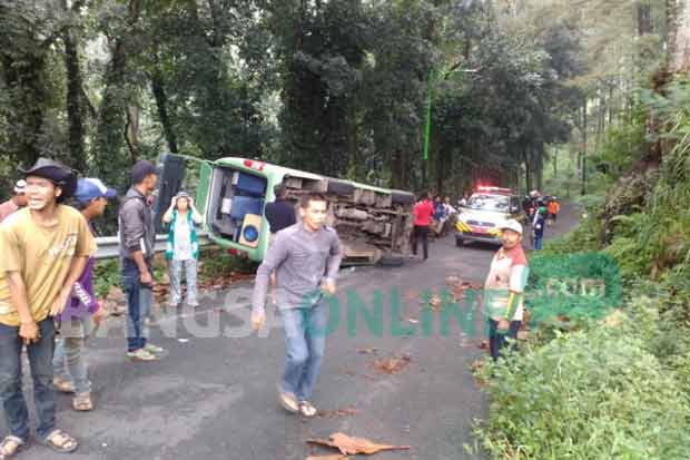 Minibus yang terguling setelah menabrak pembatas jalan.