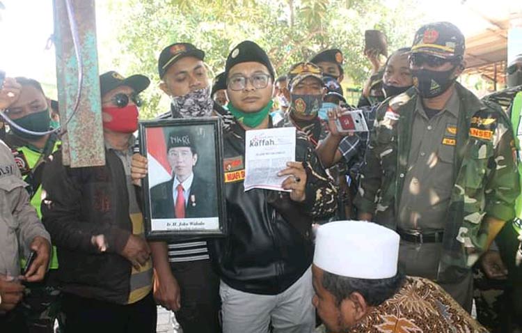 Ketua PC Ansor Bangil Saad Muafi menunjukkan foto Presiden RI Jokowi yang dicoret-coret dan berkas HTI saat mendatangi Abdul Halim di Bangil Pasuruan Jawa Timur, Sabtu (22/8/2020). foto: ahmad fuad/ bangsaonline.com