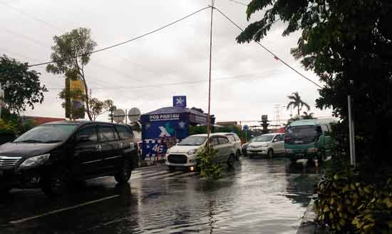 Agar tetap bisa dilewati pengendara, kabel yang menjuntai di tengah jalan tepaksa disangga  menggunakan bambu untuk. foto: NANANG I/ BANGSAONLINE