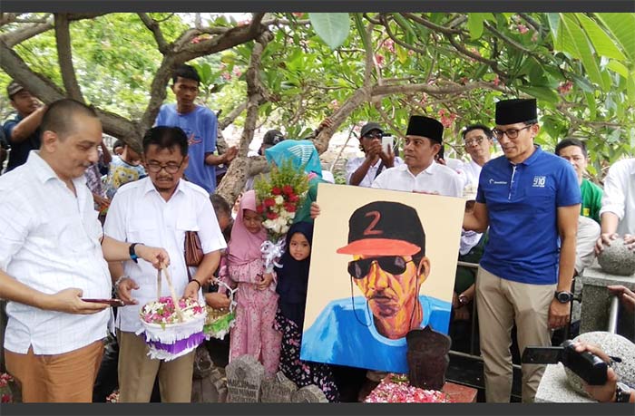 Sandiaga Uno memegang lukisan Gombloh mengenakan topi dengan angka 2 yang diprotes keluarga dan fans Gombloh. foto: ist