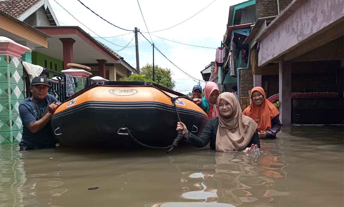 Warga saat menggunakan perahu karet untuk menerjang banjir di Kabupaten Pasuruan.
