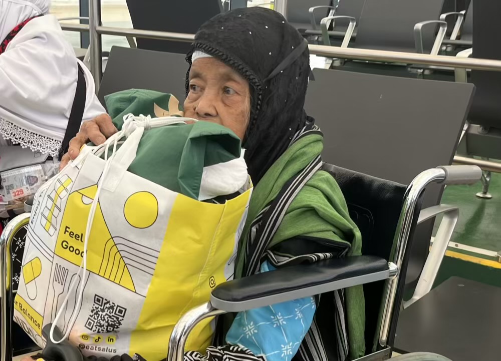 Mbah Satinah saat tiba di bandara King Abdulaziz Jeddah sambil memangku oleh-oleh sajadah yang ia beli untuk keluarga di rumah. Foto: Sulthon/MCH 2026.