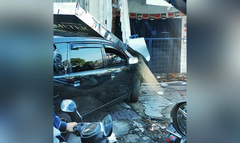 Kondisi mobil tertimpa papan reklame usai menabrak toko.