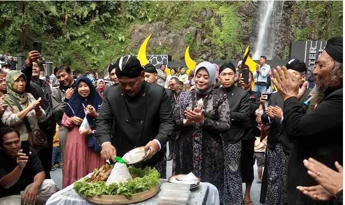 Bupati Marhaen Djumadi memotong tumpeng usai pelaksanaan mandi siraman Sedudo. Foto: BAMBANG/ BANGSAONLINE.com
