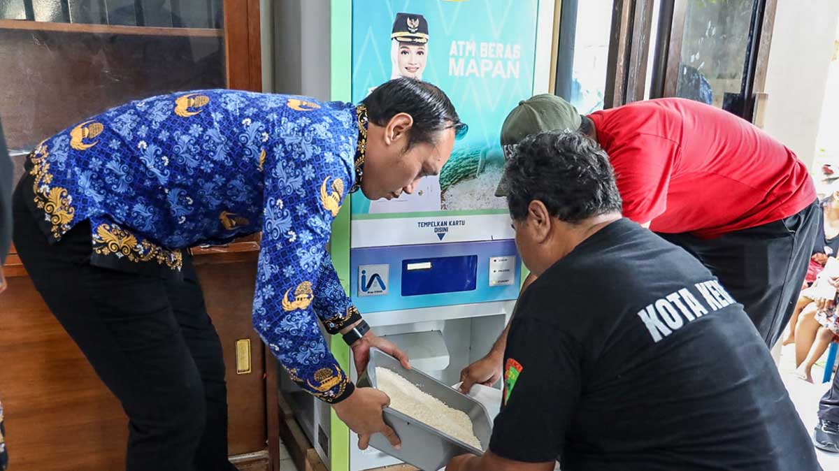 Kepala Dinsos Kota Kediri, Imam Muttaqin (kiri), saat membantu warga mengambil beras melalui ATM Beras. Foto: Ist