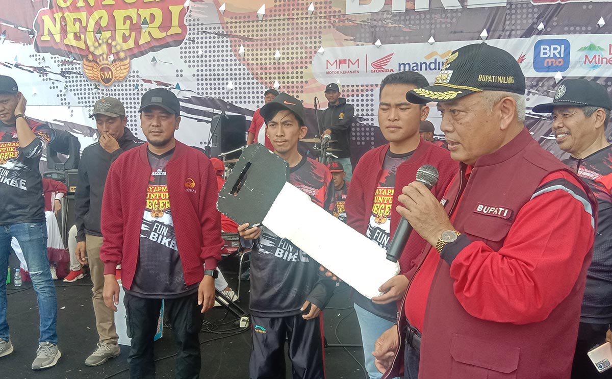 Bupati Malang Sanusi (kanan) saat menyerahkan doorprize berupa satu unit motor.