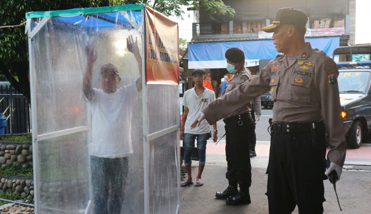 Anak jalanan yang terjaring razia saat disemprot disinfektan di bilik sterilisasi.