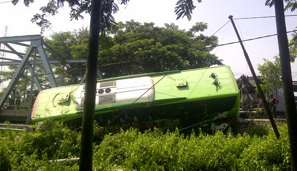 Bus Restu yang terjungkal ke pinggir sungai setelah menabrak pengaman jembatan. foto: soewandito/ BANGSAONLINE