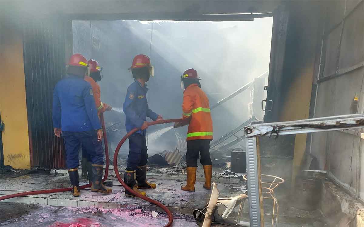Petugas usai menjinakkan api yang melalap toko cat dan tiner di Sidoarjo.