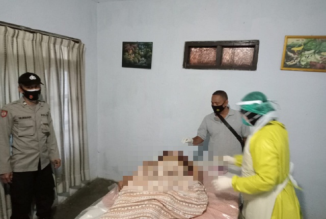 Petugas medis melakukan pemeriksaan terhadap jenazah korban disaksikan anggota kepolisian.