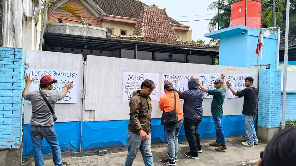 Massa Aksi saat memasang poster di pintu gerbang SPPG Bandar Lor. Foto: Muji Harjita/Bangsaonline.