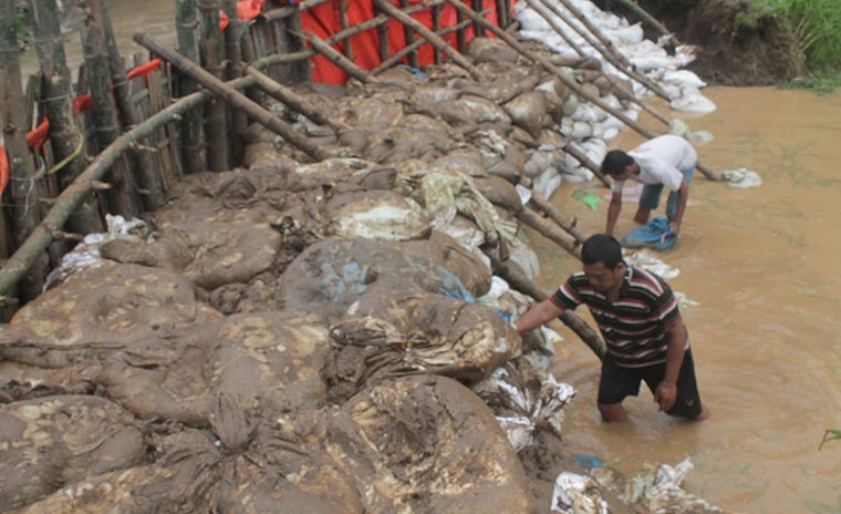 Tanggul sementara yang dibuat warga untuk menutup luapan air sungai. foto: BAMBANG/ BANGSAONLINE