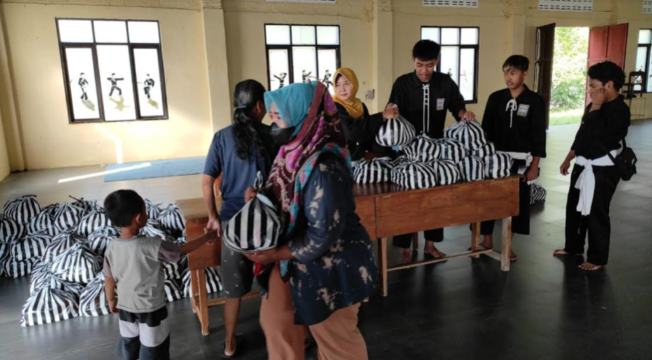 Keluarga PSHT Kota Kediri bagikan paket sembako kepada masyarakat yang membutuhkan.