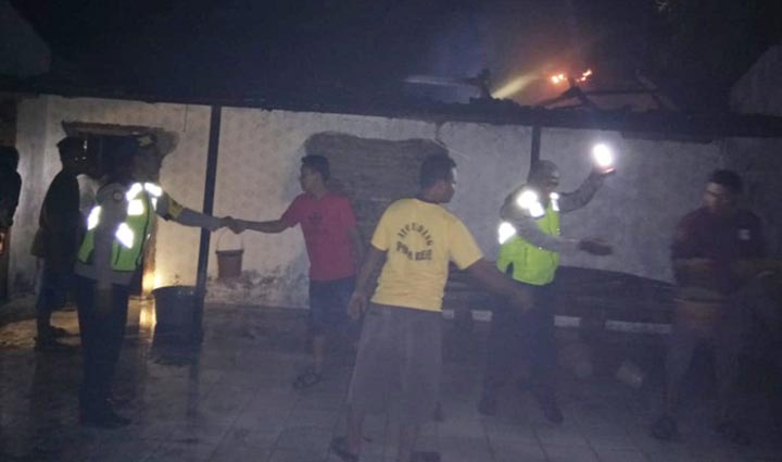 Warga dibantu petugas saat mencoba memadamkan api yang menghanguskan rumah korban.