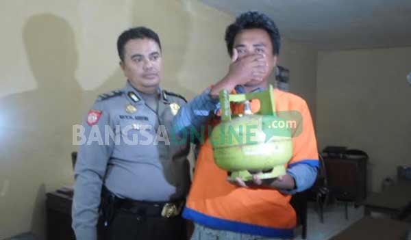SAYANG ANAK: Tersangka Moch Dulhijah menunjukkan tabung elpiji melon yang dicuri untuk pengobatan anaknya yang sakit ketika di Mapolsek Taman. foto: catur andy/ BANGSAONLINE