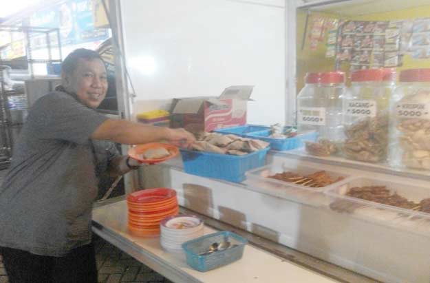 TAK CANGGUNG: Warih Andono menunjukkan makanan di Angkringan ‘Inyong Baen’, di depan Kantor DPD Golkar Sidoarjo, Sabtu (20/5) malam. foto: mustain/ BANGSAONLINE