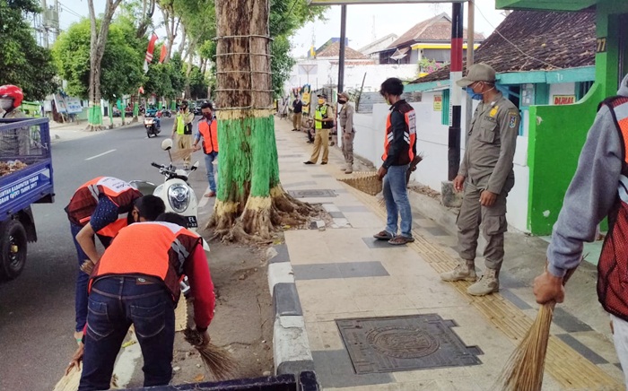Para pemuda yang terjaring razia sedang dihukum bersih-bersih.