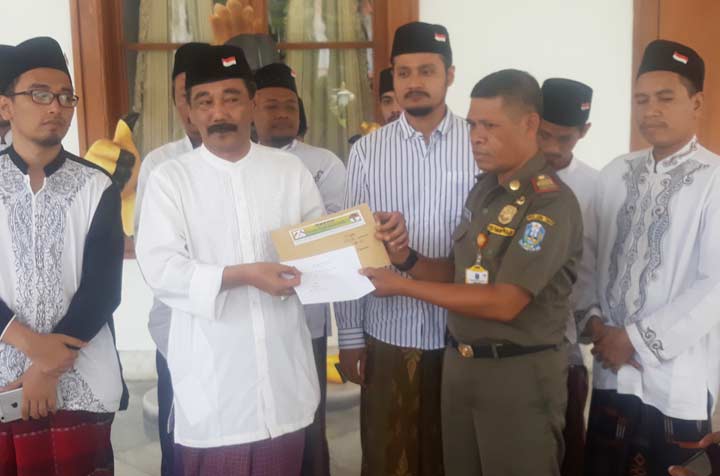 Koordinator Barisan Santri Merah Putih (BSMP), KH. Fakhrurrozi menyerahkan surat mandat dukungan kepada Pakde Karwo di rumah dinas gubernur di komplek Gedung Grahadi. foto: DIDI ROSADI/ BANGSAONLINE