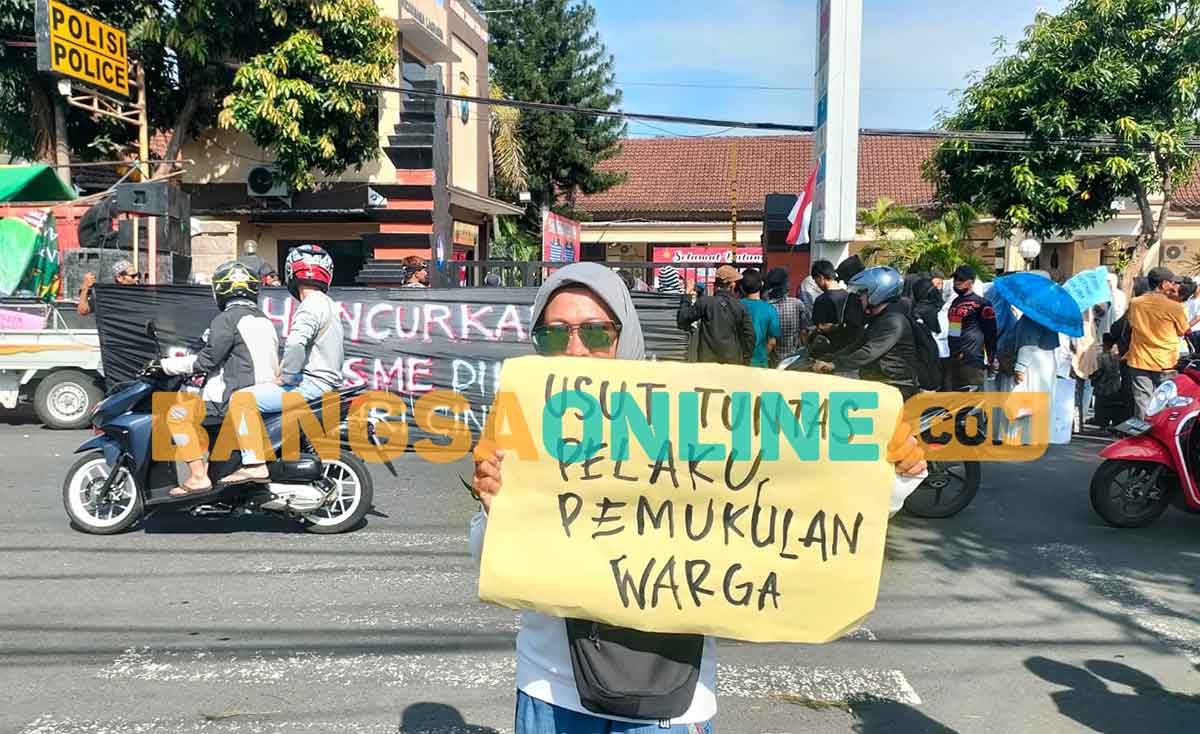 Binti, orang tua salah satu korban dugaan penganiayaan (pemukulan) oleh oknum, saat membentangkan poster di depan Mapolres Kediri Kota. Foto: MUJI HARJITA/BANGSAONLINE