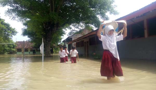 Murid sekolahan SDN Pilang Gede di Kecamatan Balen, mengangkat tasnya agar tak basah. foto: eky nurhadi/ BANGSAONLINE