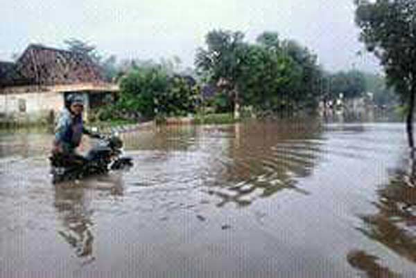 Warga yang nekat menerjang banjir terpaksa menuntun karena motornya mogok.