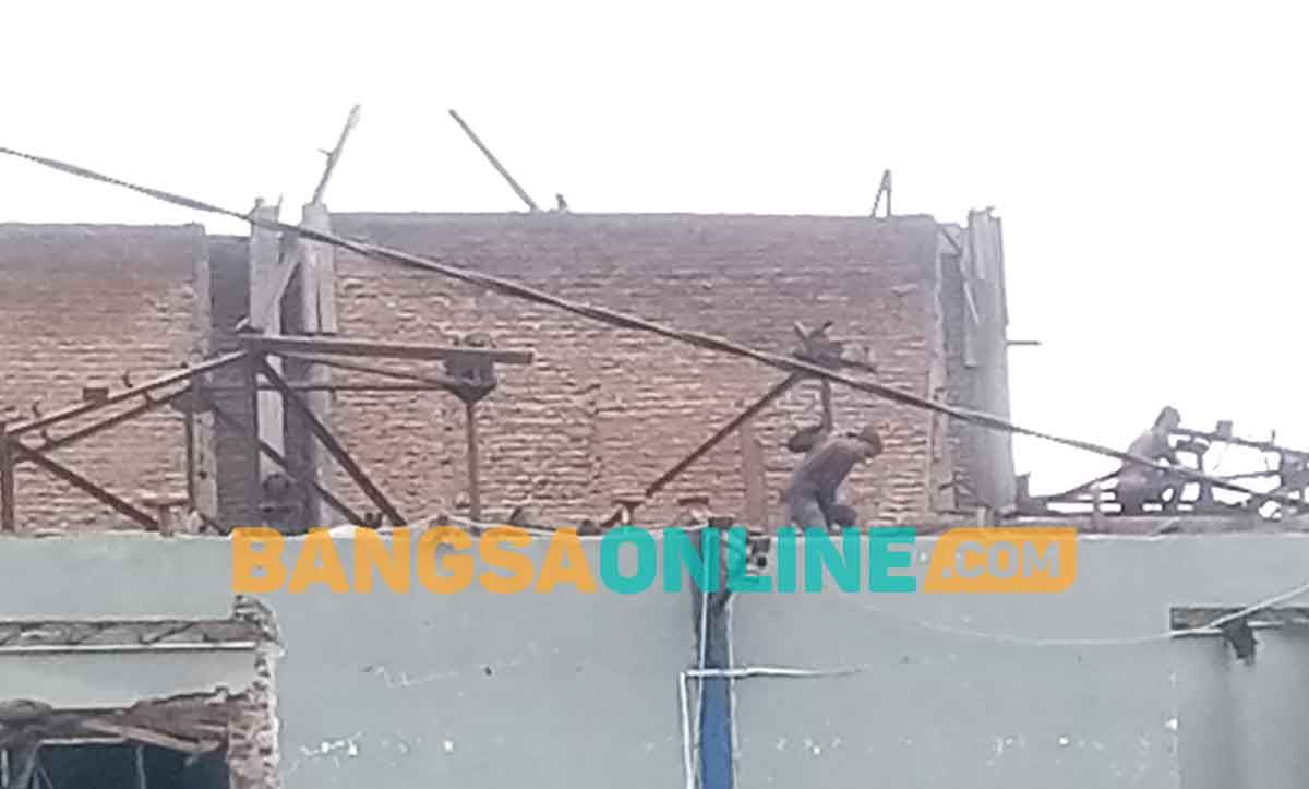 Pekerja yang membongkar atap gedung tampak tidak menggunakan alat keselamatan kerja. Foto: HENDRO SUHARTONO/BANGSAONLINE