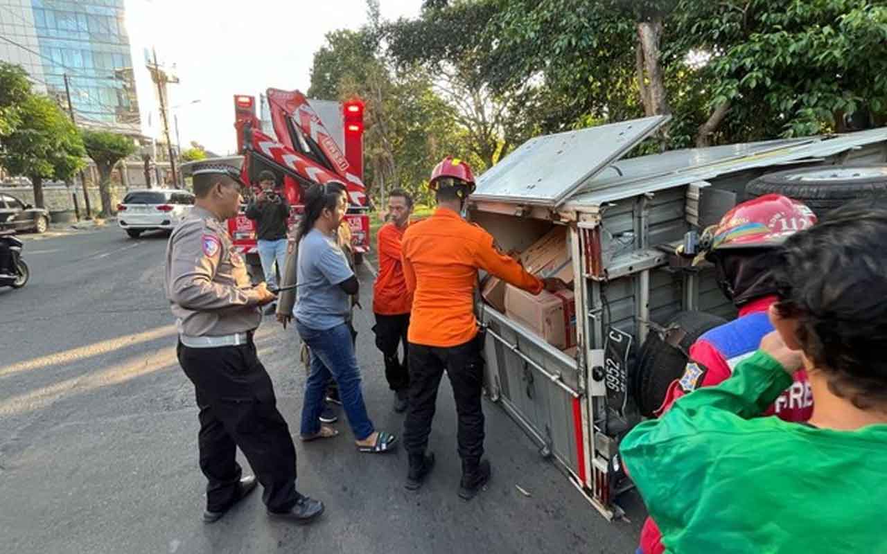 Kondisi mobil pikap bermuatan oli dan suku cadang saat terguling di Jalan Jemursari, Surabaya, Senin (21/7/2025)
