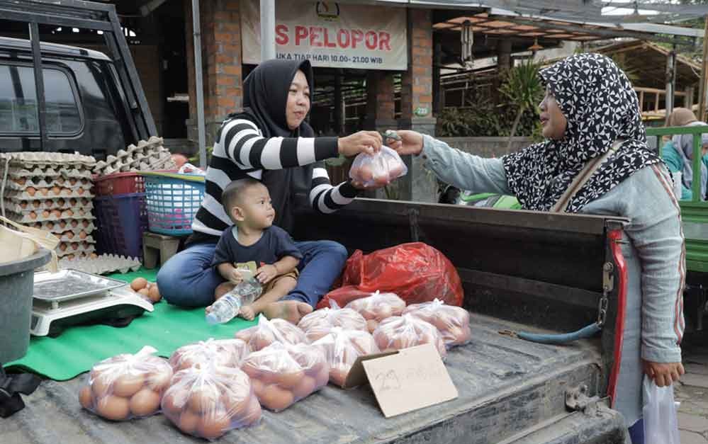 Ilustrasi fluktuasi. Seorang pedagang saat telur melayani pembeli. (Ist)