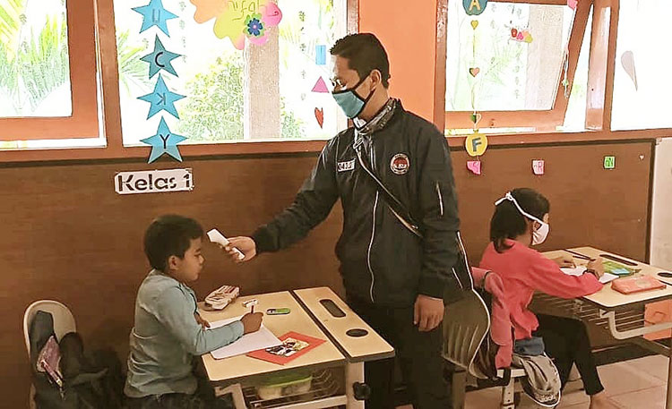 Guru SDN Gungsari 04 sedang mengecek suhu tubuh satu per satu siswa sebelum memulai KBM.