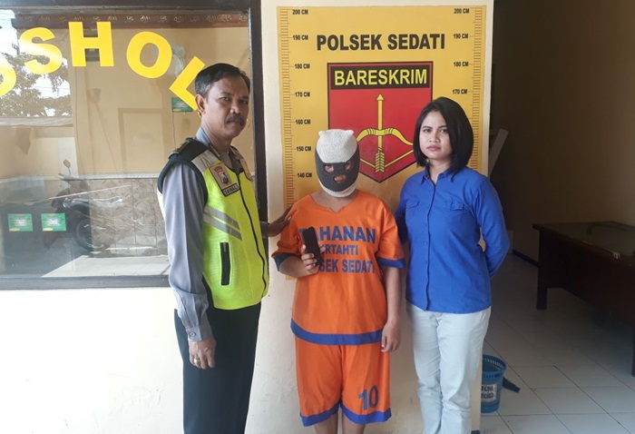 Pelaku saat diapit petugas Polsek Sedati, Sidoarjo.