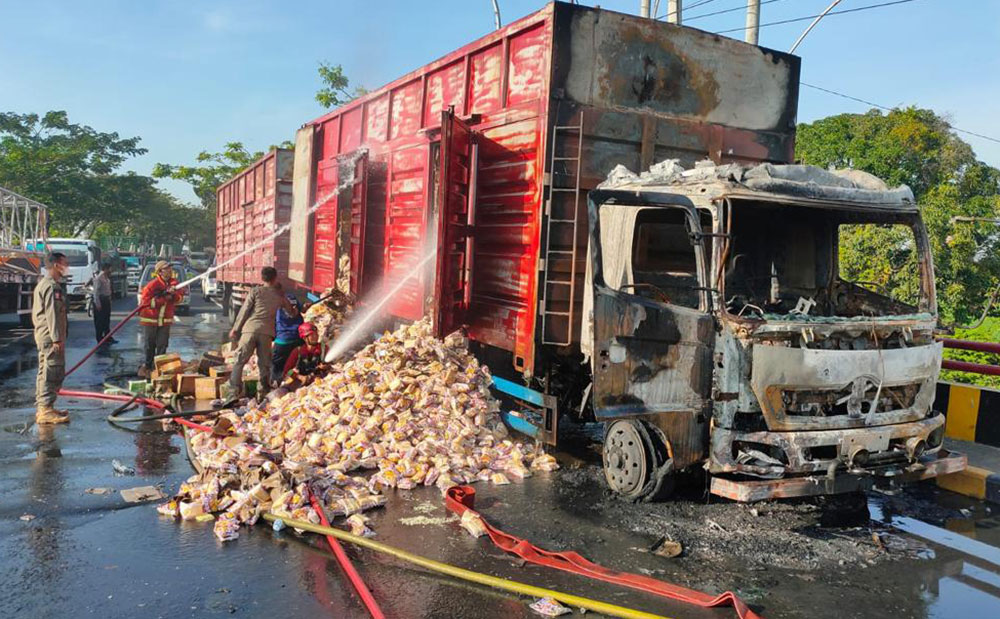 Petugas damkar melakukan pembasahan pada boks truk.