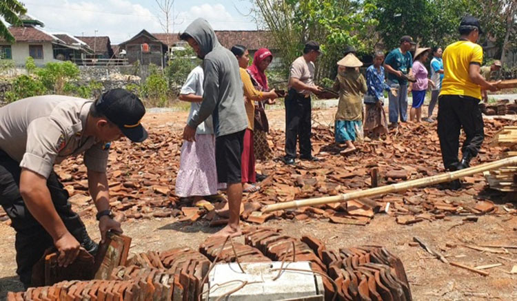 Polisi bersama masyarakat bergotong-royong membersihkan puing-puing reruntuhan rumah yang diterjang angin puting beliung. foto: BAMBANG/ BANGSAONLINE