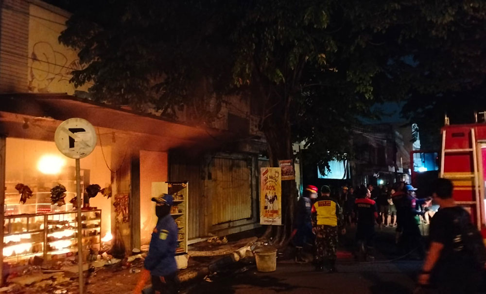 Anggota Polsek Bangil dibantu Anggota Koramil Bangil saat memadamkan kebakaran toko kelontong di Jalan Raya Diponegoro, Bangil.
