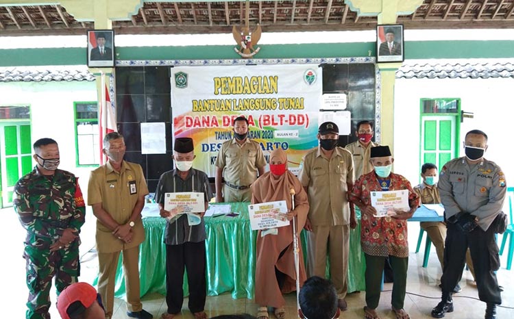 Babinsa Jokarto Koramil 0821/10 Tempeh, Serda Imam Wahyudi saat mendampingi kegiatan penyaluran BLT DD Tahap II yang bertempat di Balai Desa Jokarto, Kecamatan Tempeh, Kabupaten Lumajang, Senin (8/6/2020).
