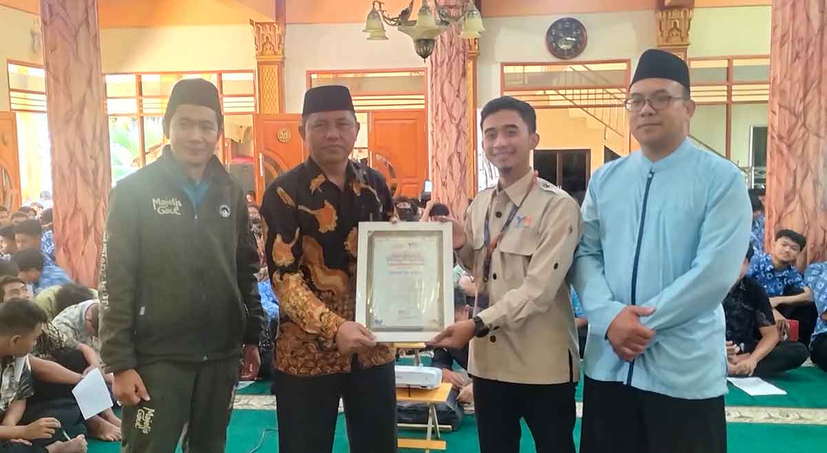 Kepala Cabang Yatim Mandiri Kota Batu, M. Haafidhuddin, saat menyerahkan piagam penghargaan ke Kepala SMAN 2 Batu, Wartono.