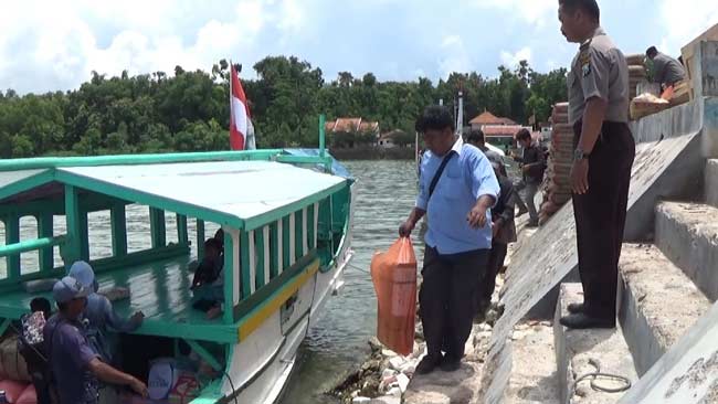 Petugas saat menaikkan naskah Unas ke perahu. foto: rahmatullah/ BANGSAONLINE