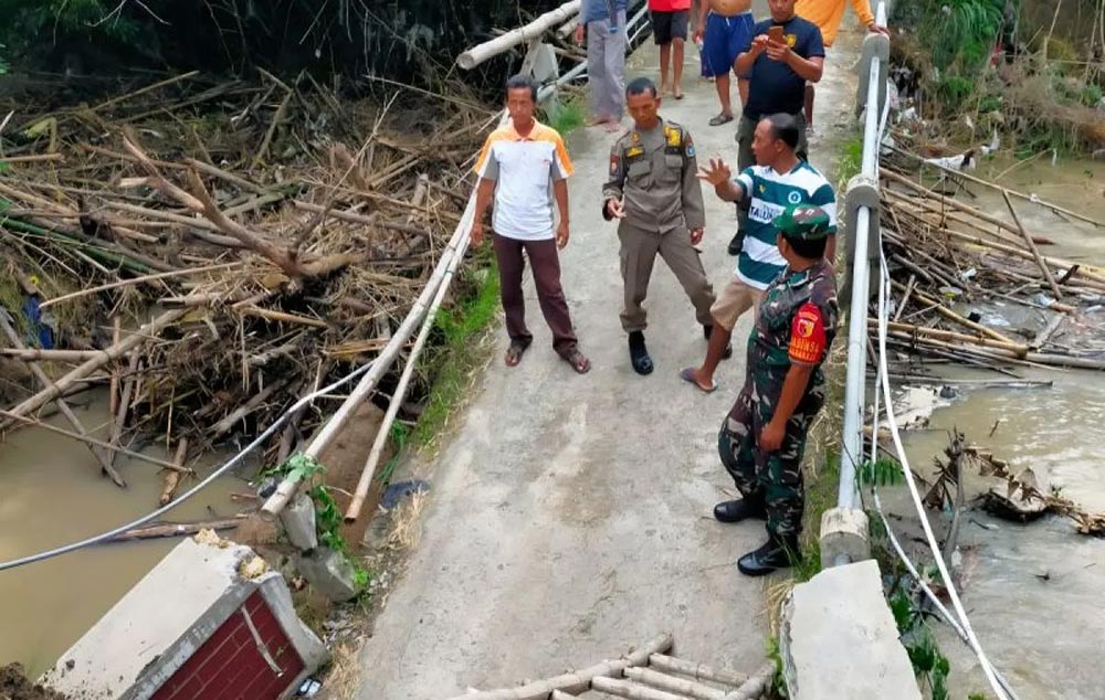 Anggota Koramil 0812/07 Bluluk saat meninjau kondisi jembatan penghubung Lamongan–Bojonegoro yang putus akibat banjir Sungai Semar Mendem, Jumat (21/11/2025). 