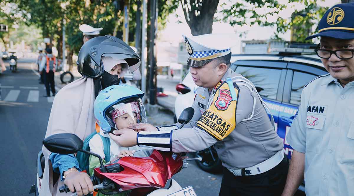 Kasatlantas Polres Gresik, AKP Rizki Julianda Putera Buna, ketika memberikan helm kepada salah satu pengendara. Foto: Ist