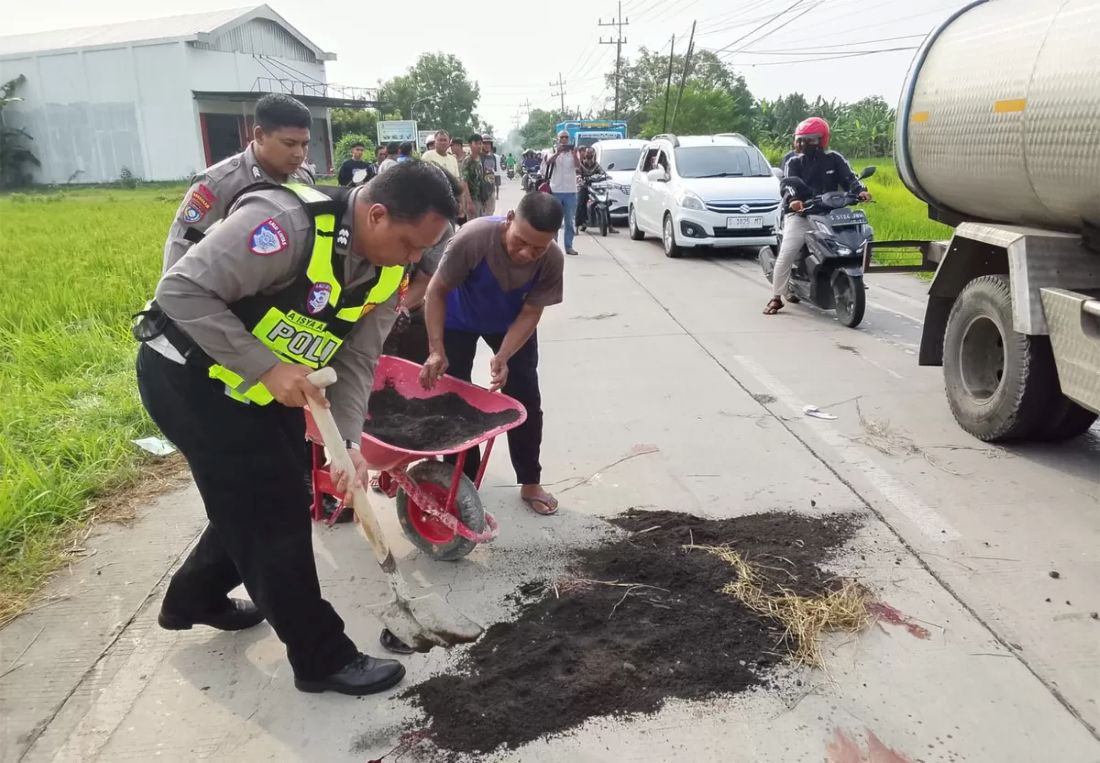 Polisi saat membersikan sisa noda korban di TKP laka