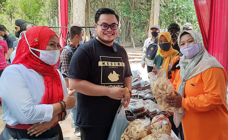 Dhito saat disodori kerupuk oleh ibu-ibu pelaku UMKM di area Sumber Putriman Dusun Mantren. Karena harus icip-icip, maka Dhito harus melepas maskernya. (foto: MUJI HARJITA/ BANGSAONLINE)