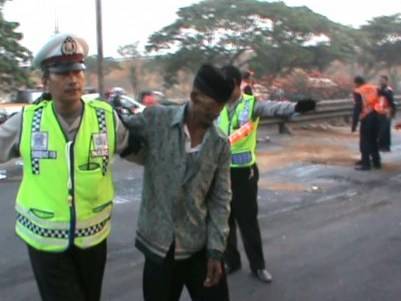 TERLUKA - Polisi tengah membantu seorang korban yang terluka sesaat setelah Bus Harapan Jaya, terguling di Jalan Raya Bungurasih, depan kantor Mahkamah Militer (Mahmil) Waru, Sidoarjo, Senin (13/10/2014). foto istimewa