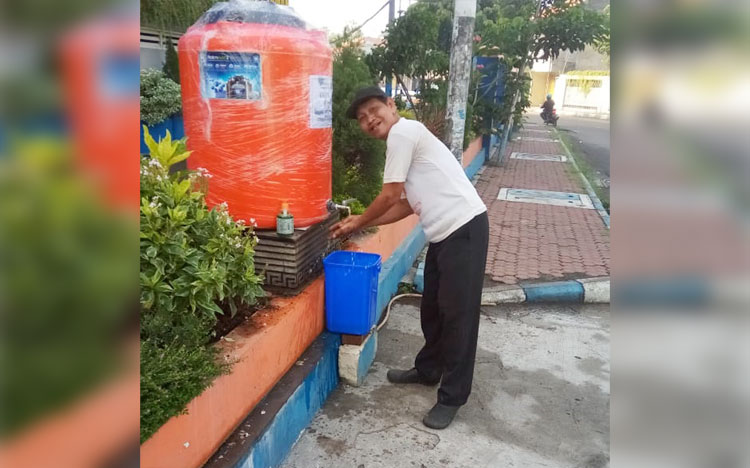 UNTUK UMUM: Seorang warga memanfaatkan fasilitas cuci tangan yang disediakan Smamita Sidoarjo, Rabu (8/4). foto: ist