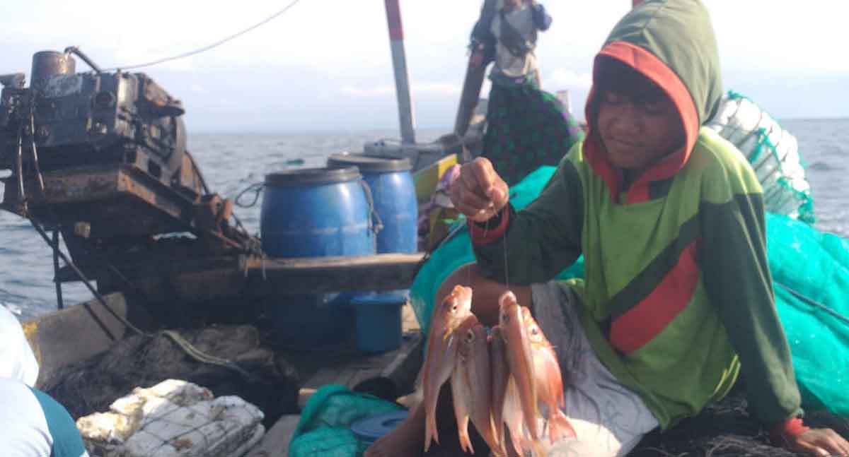 Nelayan di Situbondo saat menunjukkan ikan hasil tangkapan dari atas perahunya.