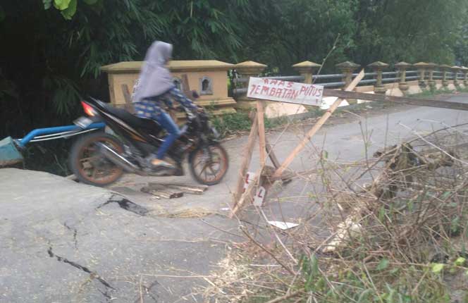Salah seorang warga nekat melintasi jembatan yang terputus. foto: AHMAD/ BANGSAONLINE