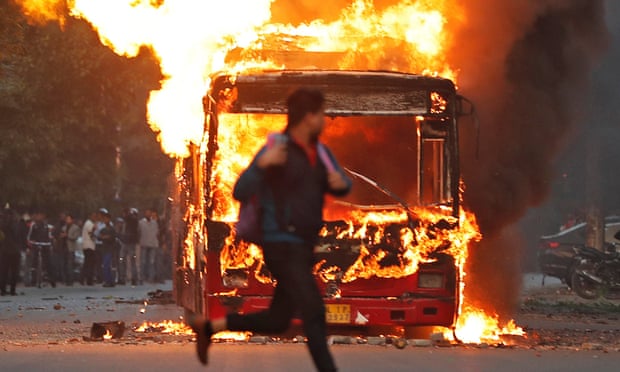 Seorang pria berlari melewati sebuah bus yang terbakar yang dibakar oleh para demonstran selama protes terhadap undang-undang kewarganegaraan baru, di Delhi, India. foto: theguardian