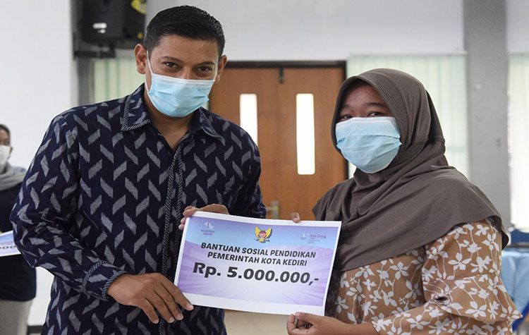 Wali Kota Kediri Abdullah Abu Bakar saat menyerahkan bantuan pendidikan kepada salah satu penerima. (foto: ist)