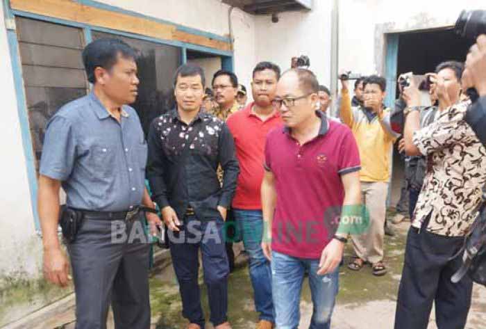 Dua WNA asal China (kaos merah dan baju hitam) saat digelandang petugas dari PT. Plastic Recycling di Desa Cangkringrandu, Kecamatan Perak, Kabupaten Jombang, Kamis (19/1). foto: ROMZA/ BANGSAONLINE