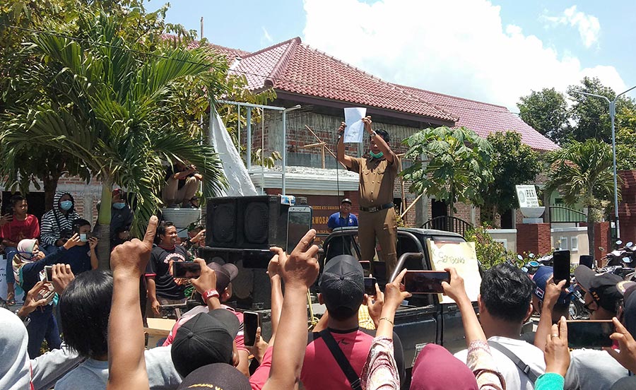 Kades Purwasari, Sukatman, menunjukan surat pengunduran diri Miseni dari jabatannya di hadapan pendemo. foto: NOVIAN CATUR/ BANGSAONLINE